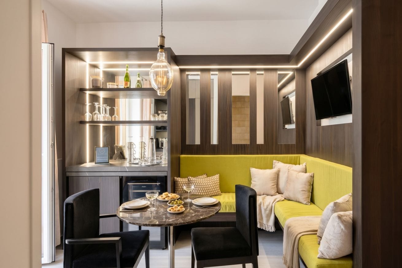 A modern kitchen with a dining table and chairs, a built-in oven, and a television mounted on the wall.