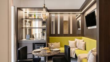 A modern kitchen with a dining table and chairs, a built-in oven, and a television mounted on the wall.