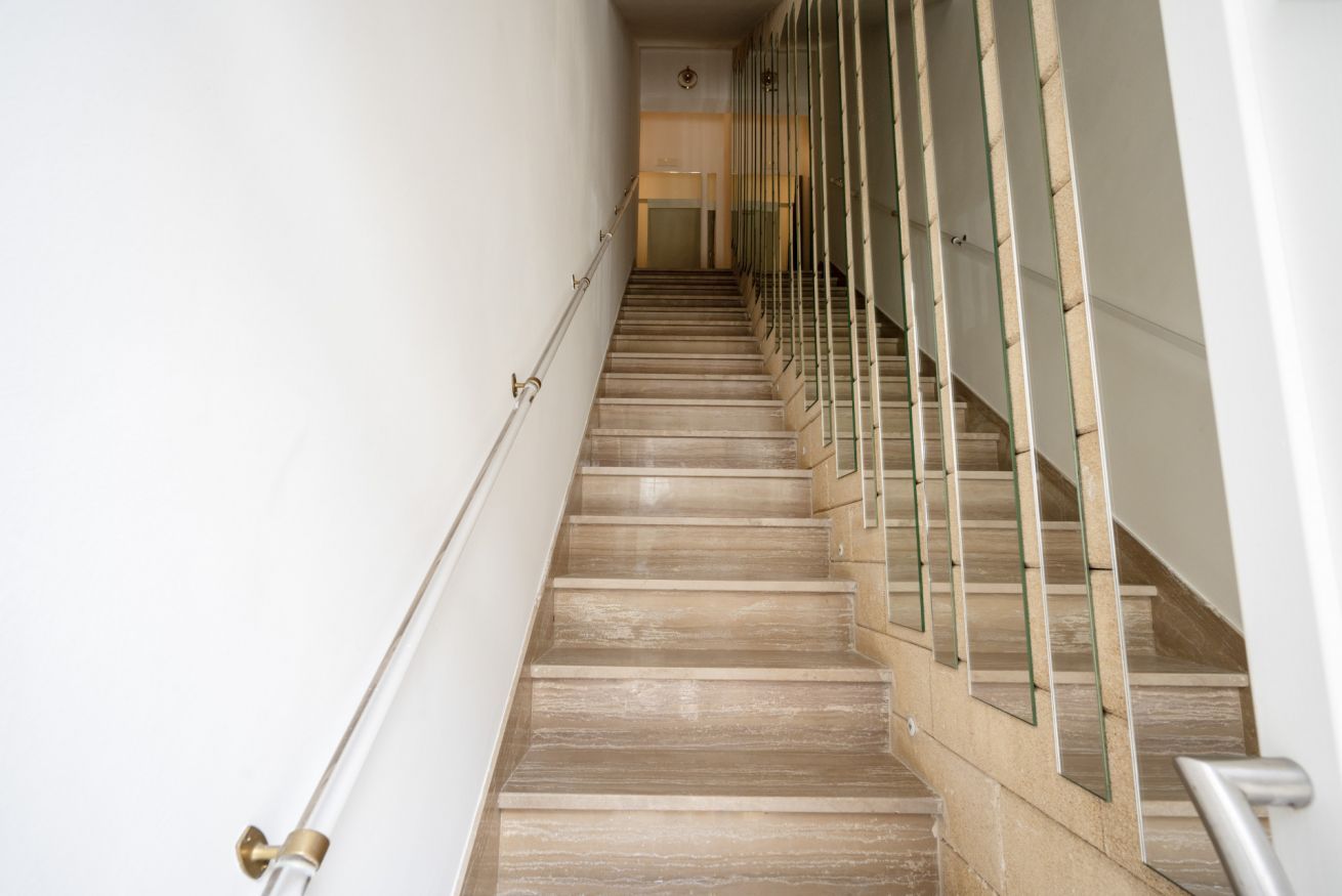 A staircase with a handrail and glass railings, leading to an upper floor.
