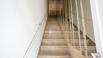 A staircase with a handrail and glass railings, leading to an upper floor.