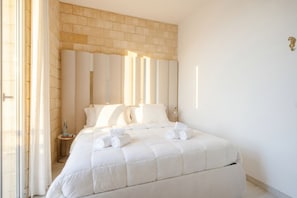 Een hotelkamer met een groot bed, een accentmuur van baksteen en een nachtkastje met een lamp.