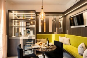 Une cuisine moderne avec un coin repas, un téléviseur fixé au mur et un canapé vert vif.