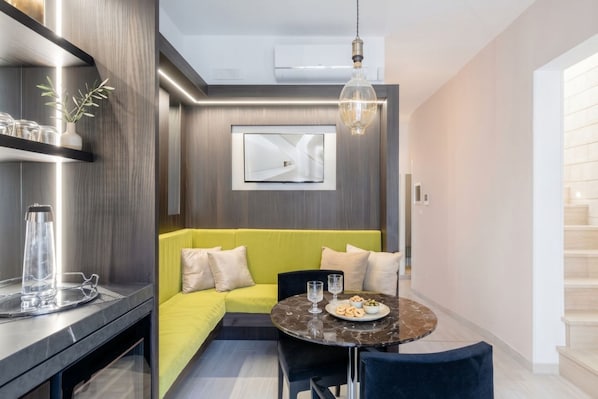 Een moderne woonkamer met een bank, een eettafel en een aan de muur bevestigde televisie.
