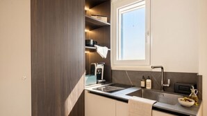 Une cuisine compacte dotée d’un four encastré, d’un évier et d’une fenêtre située au-dessus du plan de travail.