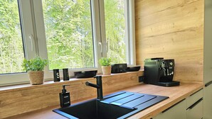 Cozinha moderna com pia preta, bancada de madeira e máquina de café.