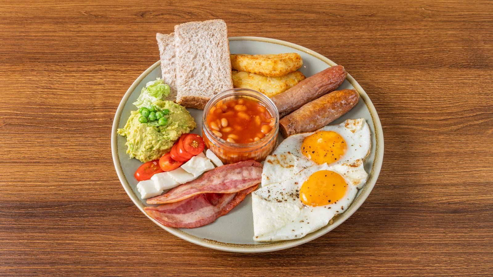 Prato com ovos, bacon, torradas, feijão e abacate.