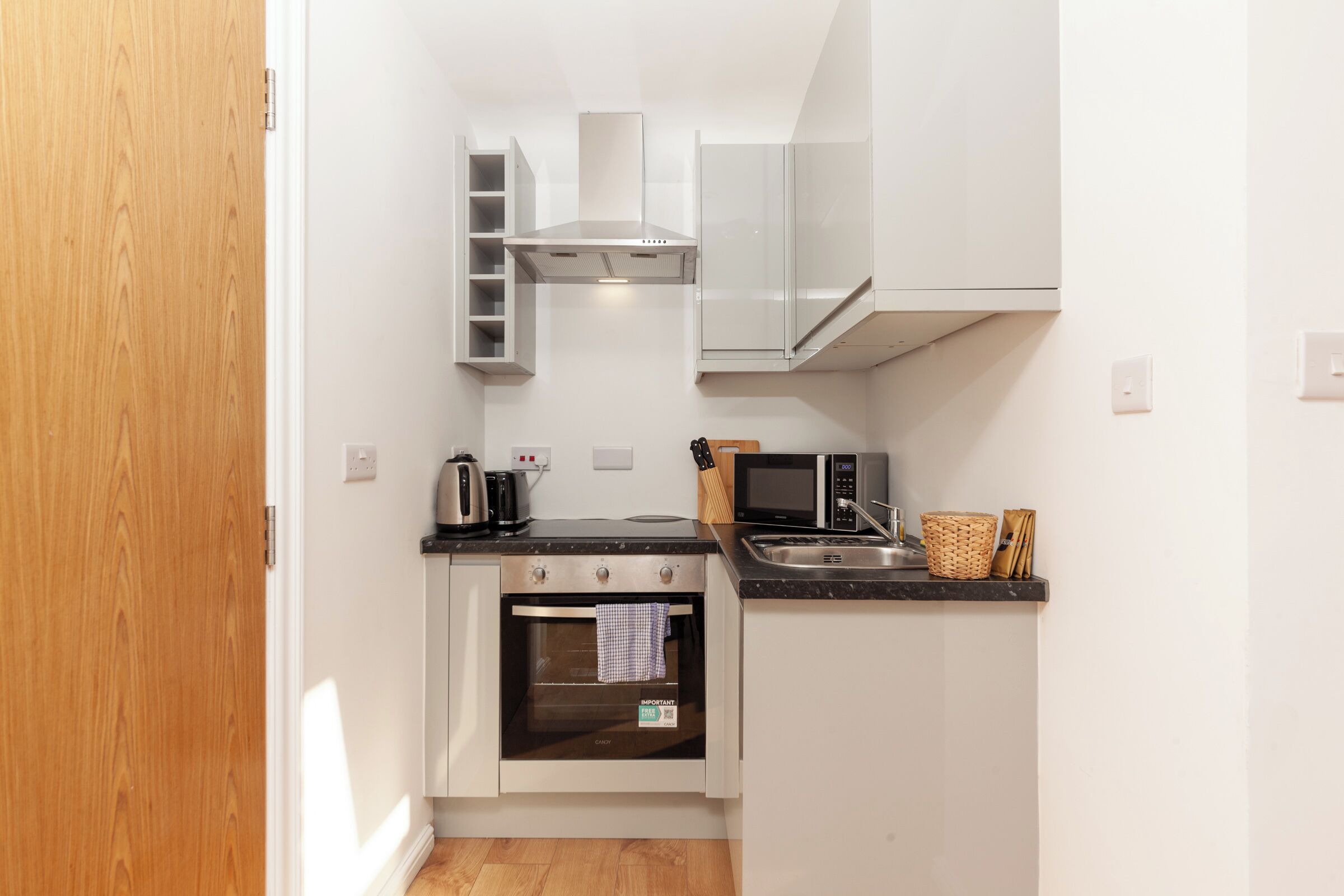A compact kitchen with a built-in oven, microwave, and stainless steel range hood.