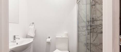 A modern bathroom with a white sink, toilet, and glass-enclosed shower.