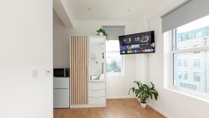 Une cuisine moderne équipée d’un four à micro-ondes encastré, d’un réfrigérateur blanc et d’un meuble en bois.