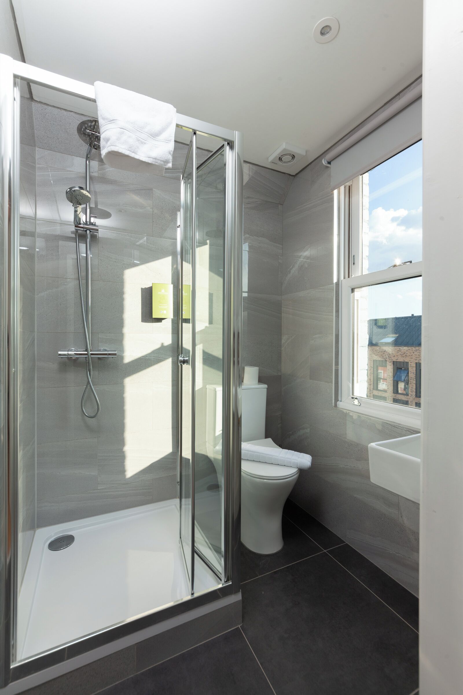 Een moderne badkamer met een glazen douchecabine, toilet en wastafel.