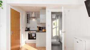 Une cuisine compacte avec des meubles blancs, un four à micro-ondes et une cuisinière.