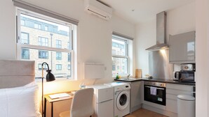 Une chambre d’hôtel compacte comprenant un lit, un bureau, un lave-linge, un four, un four à micro-ondes et une vue sur le bâtiment extérieur.