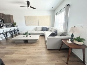 A modern living room with a sofa, coffee table, and a dining area with chairs.