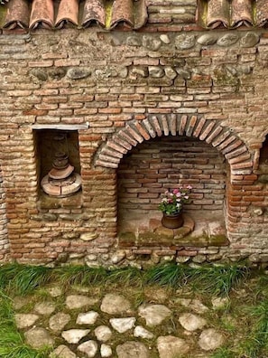 Un muro de piedra con un arco de ladrillo y una ventana pequeña.