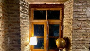 A rustic room with a wooden desk, a globe, a lamp, and a window with a wooden frame.