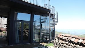 A modern building with large glass doors, a spiral staircase, and a stone wall.