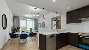 Eine moderne Küche mit Geschirrspüler, Herd und einem Essbereich mit blauen Stühlen.