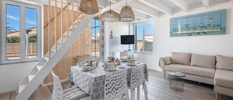 Un amplio espacio de sala con una escalera, una mesa de comedor dispuesta con vajilla y un sofá.
