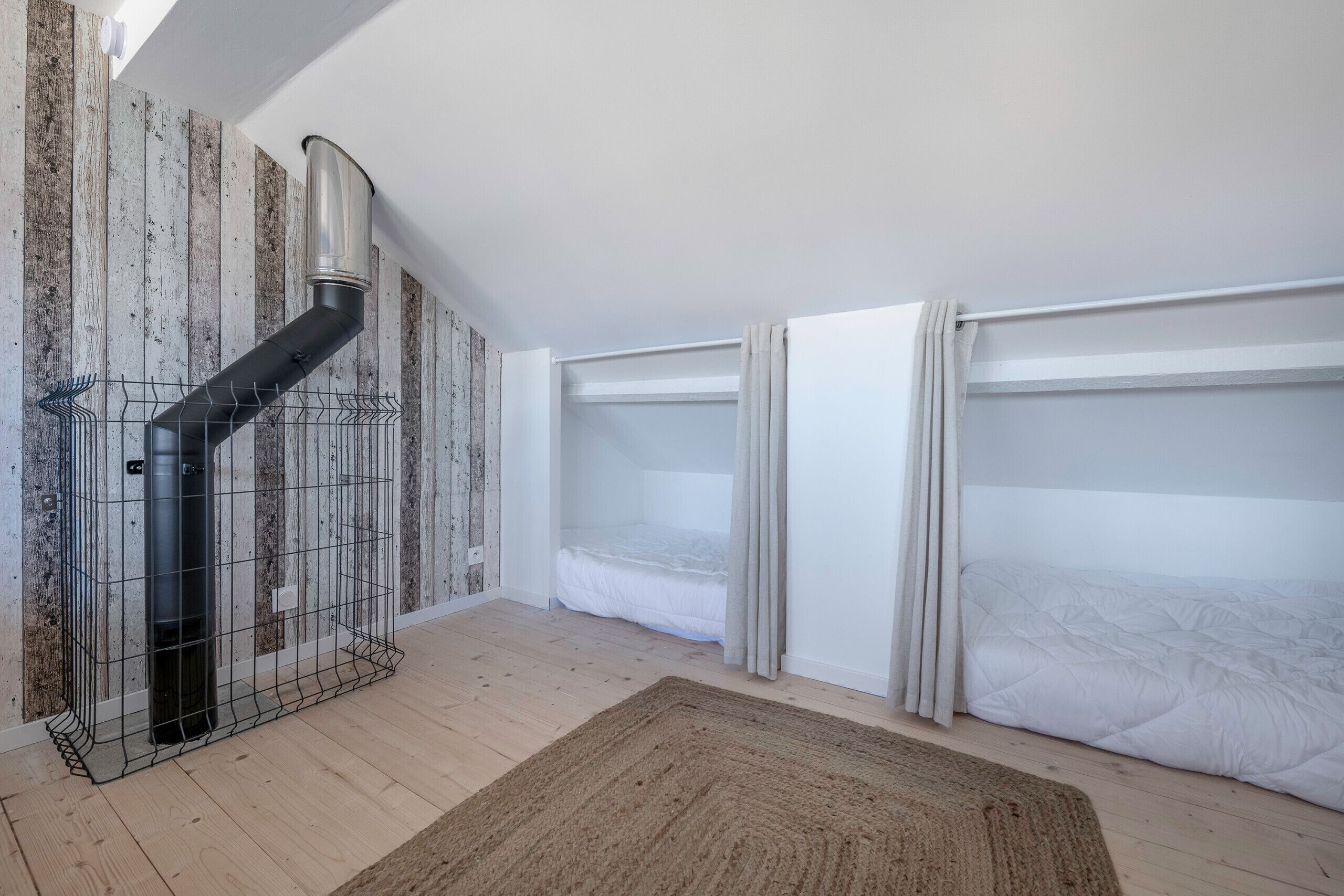 A room with a loft bed, a metal heater, and a wooden floor.