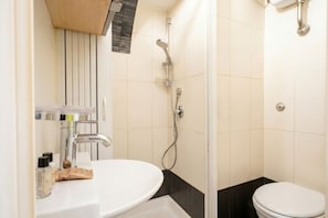 A bathroom with a white sink, a shower, and a toilet.