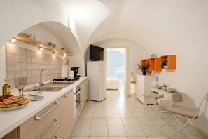 A modern kitchen with a built-in oven, a refrigerator, and a dining area with a table and chairs.