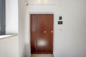 A wooden door with a brass handle, a security camera above it, and a sign indicating 'The Suite' on the wall. - The Suite - Cozy Apartment (Bari)