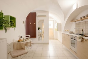 A modern kitchen with a dining area, a wooden door, and a green plant.