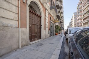 Une rue étroite avec une grande porte marron, une enseigne indiquant « Gefran », et une voiture garée.