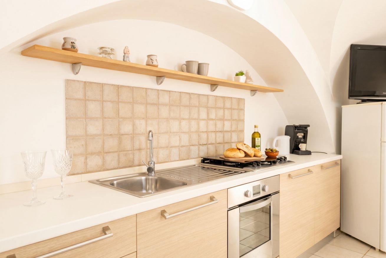 A modern kitchen with a tiled backsplash, stainless steel sink, wooden cabinets, and a built-in oven.