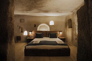 Een rustieke kamer met een groot bed, een houten hoofdbord en twee nachtkastjes met lampen.