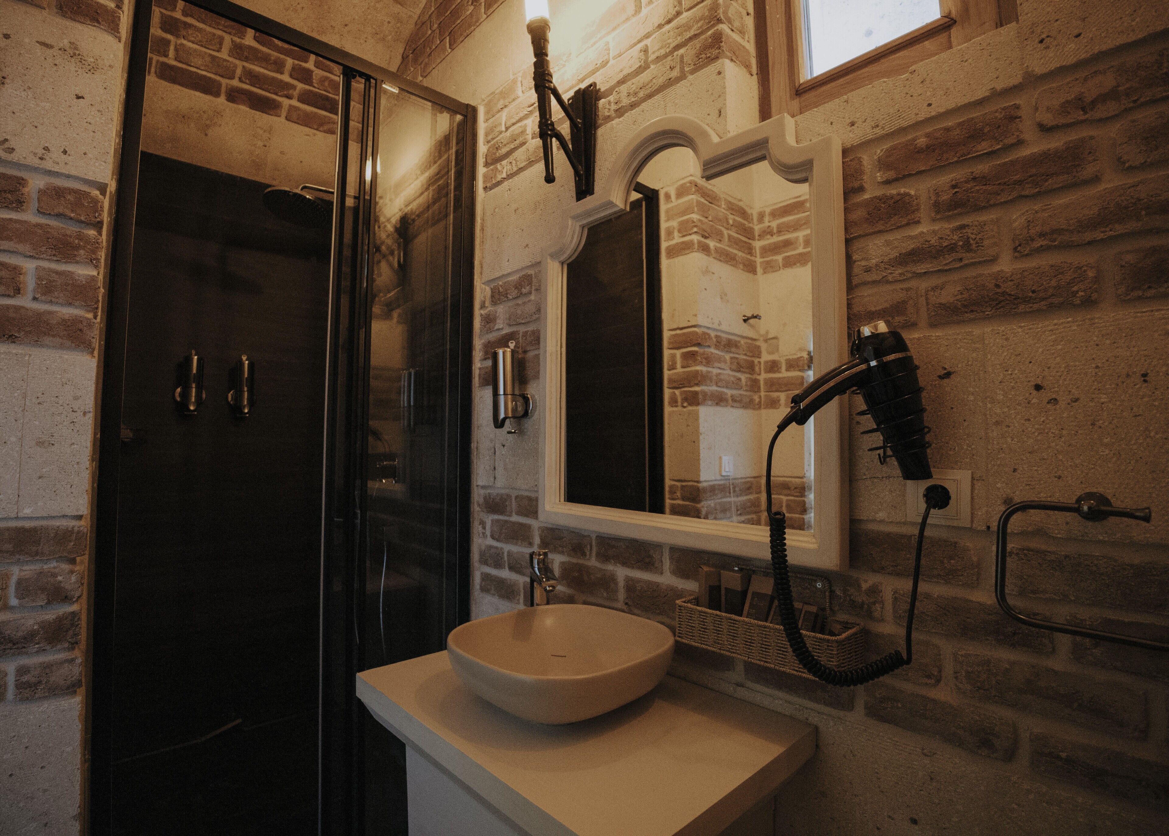 Un baño con un espejo grande, un lavabo y un secador de pelo fijado en la pared.