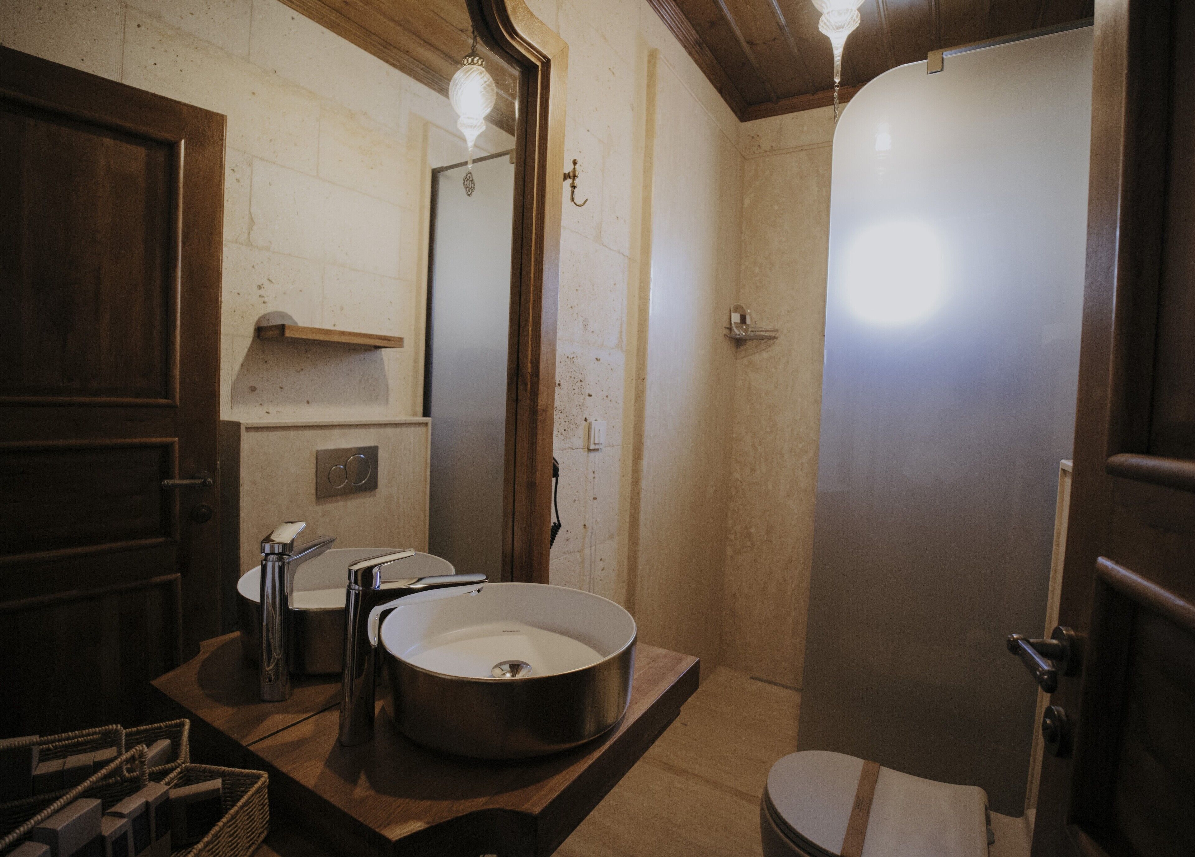 A bathroom with a wooden vanity, two sinks, a mirror, and a toilet.