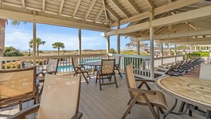 Ein überdachter Außenbereich mit Pool, Liegestühlen und Blick auf den Strand.