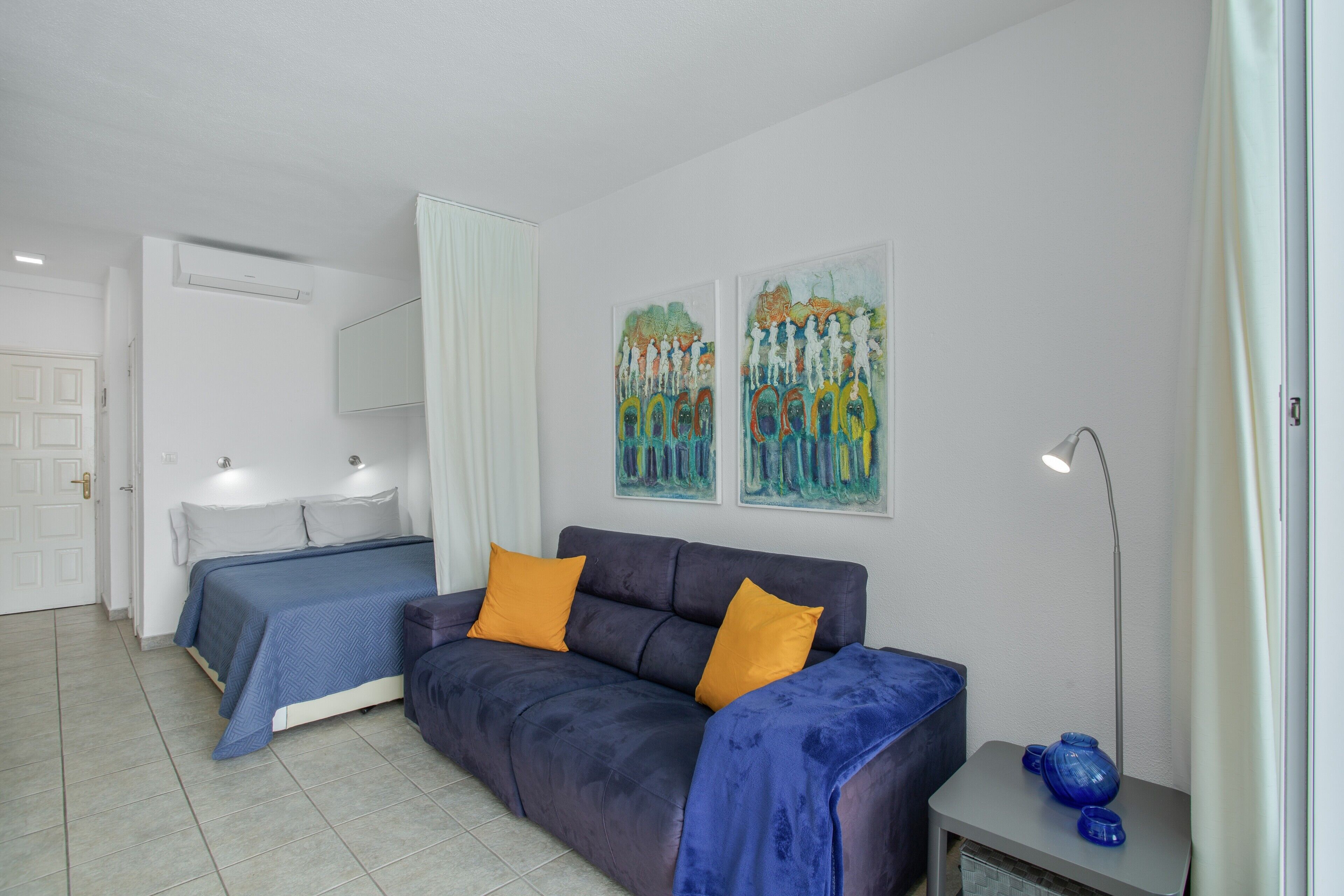 Een slaapkamer met een bed, een bank, een nachtkastje en een lamp.