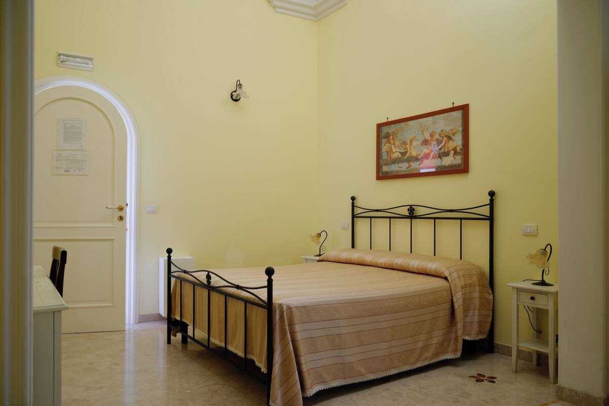 Une chambre à coucher avec un lit, une porte, un tableau et une table de chevet.