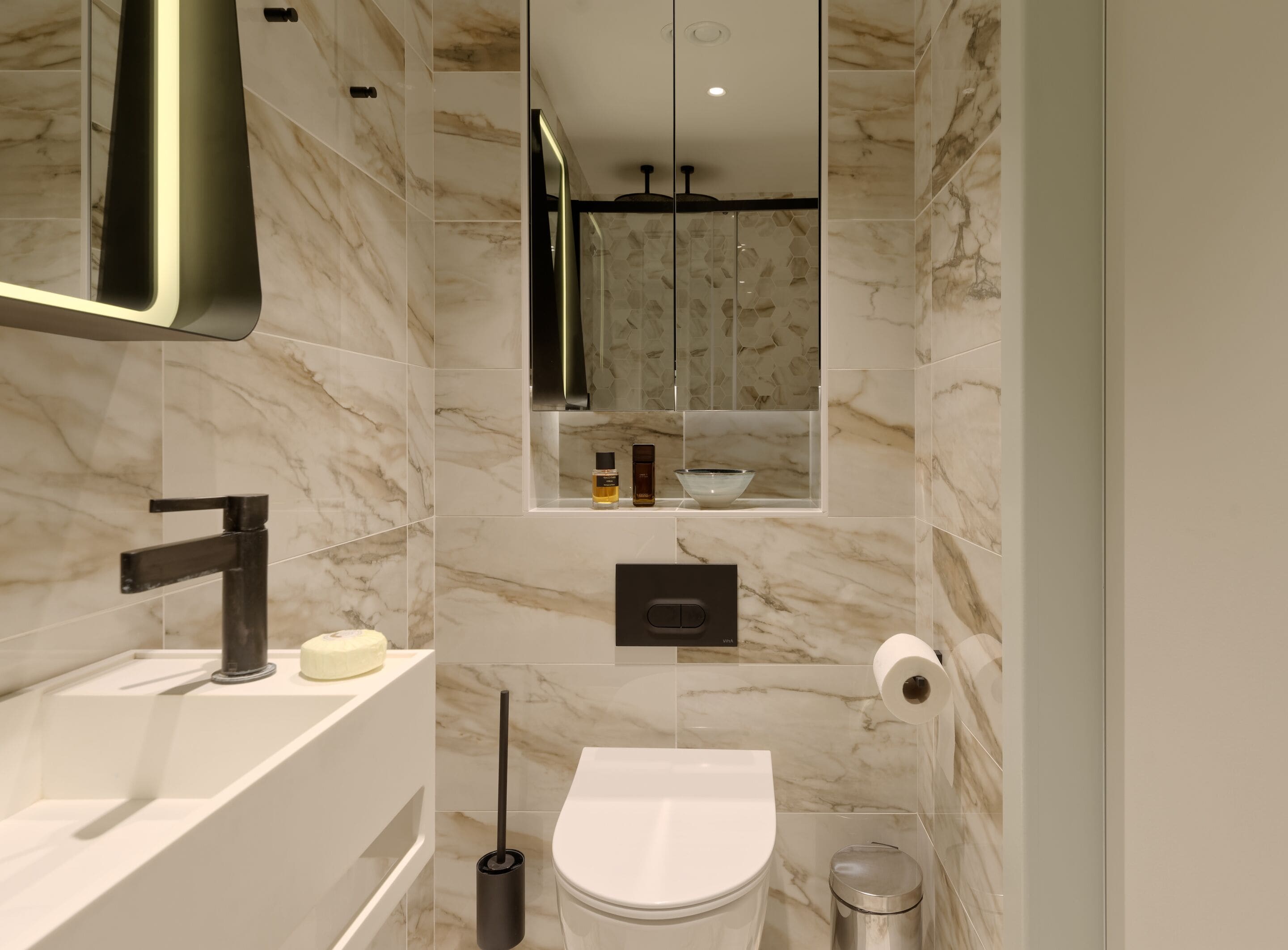 A modern bathroom with a white sink, black faucet, and a toilet.