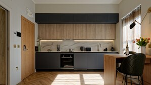 Una cocina moderna con armarios de madera, protector contra salpicaduras de mármol y suelo de madera.