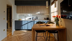 Una cocina moderna con una isla central, armarios de madera y un comedor con mesa de madera y taburetes de bar.