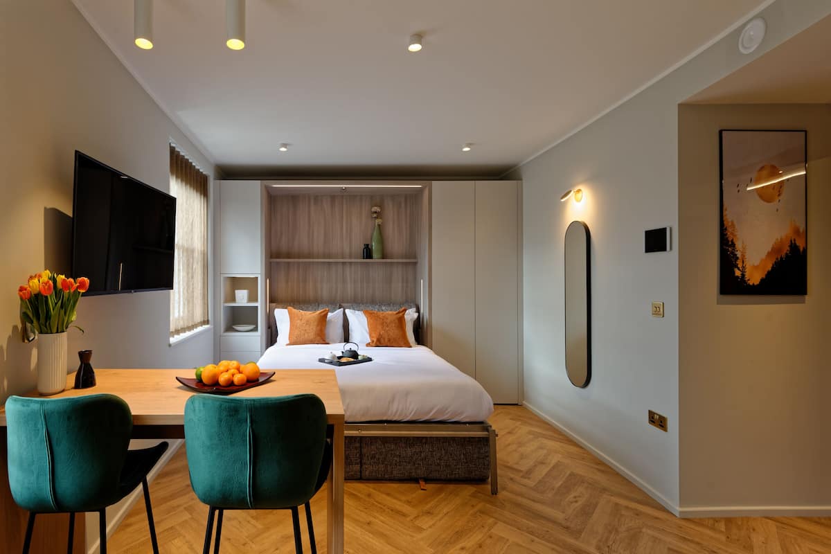 A modern bedroom with a bed, bedside table, and a wall-mounted TV.