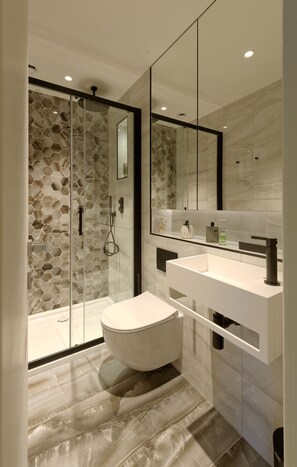 Une salle de bain moderne avec une douche à parois de verre, un lavabo blanc et un grand miroir.