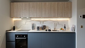 Una cocina moderna con horno empotrado, un lavamanos y un respaldo de mármol.