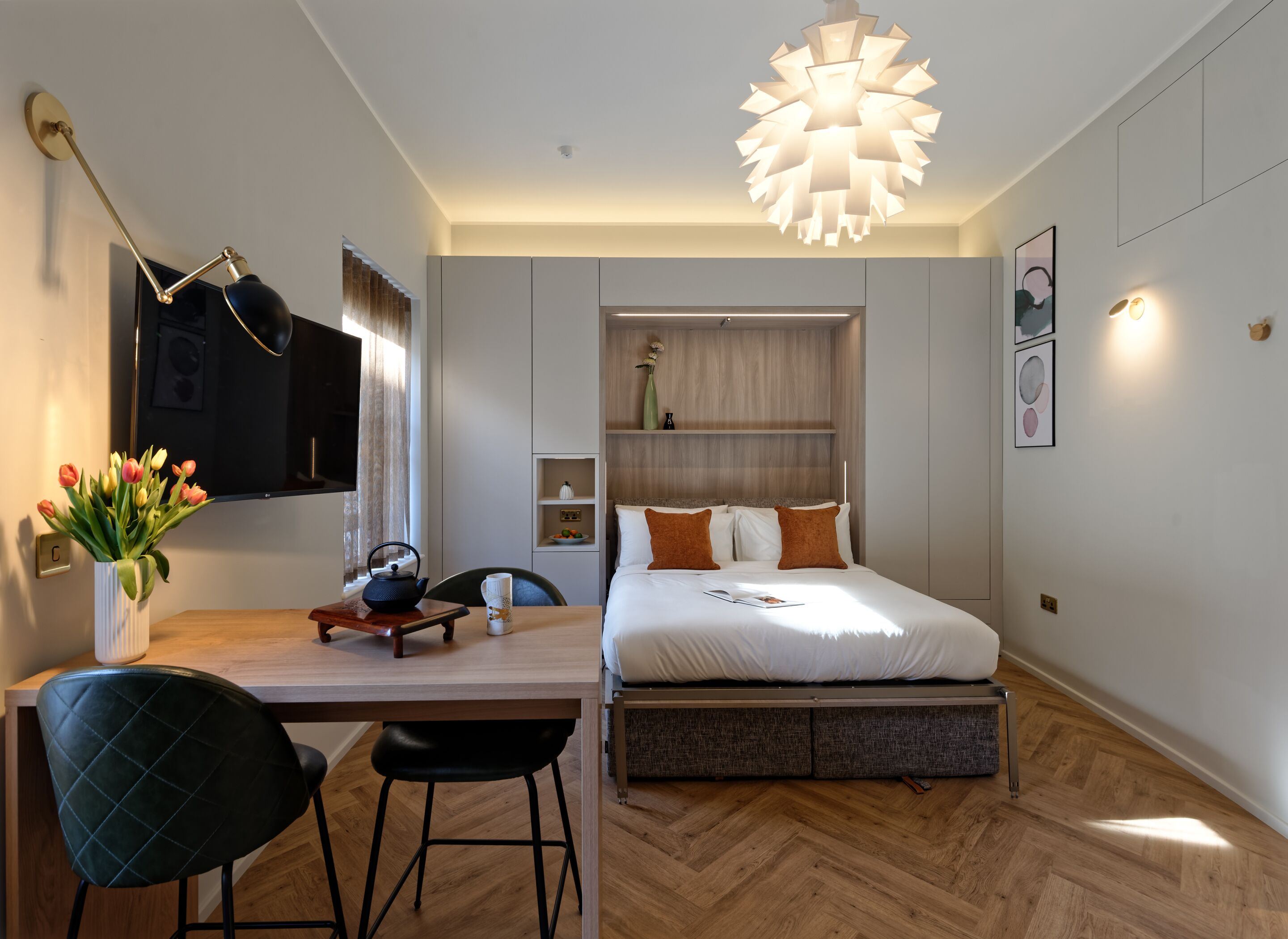 A modern bedroom with a bed, bedside table, and a desk with a chair.