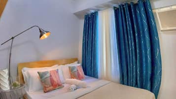 Une chambre à coucher avec un lit, une table de chevet, une lampe et une fenêtre avec des rideaux.