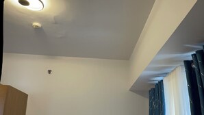 A neatly made bed with patterned pillows, a bedside lamp, and a view of the room's ceiling. - Modern Studio with Sunset View  (Manila)