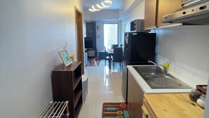 A kitchen with wooden cabinets, a stainless steel sink, and a microwave. - Modern Studio with Sunset View  (Manila)