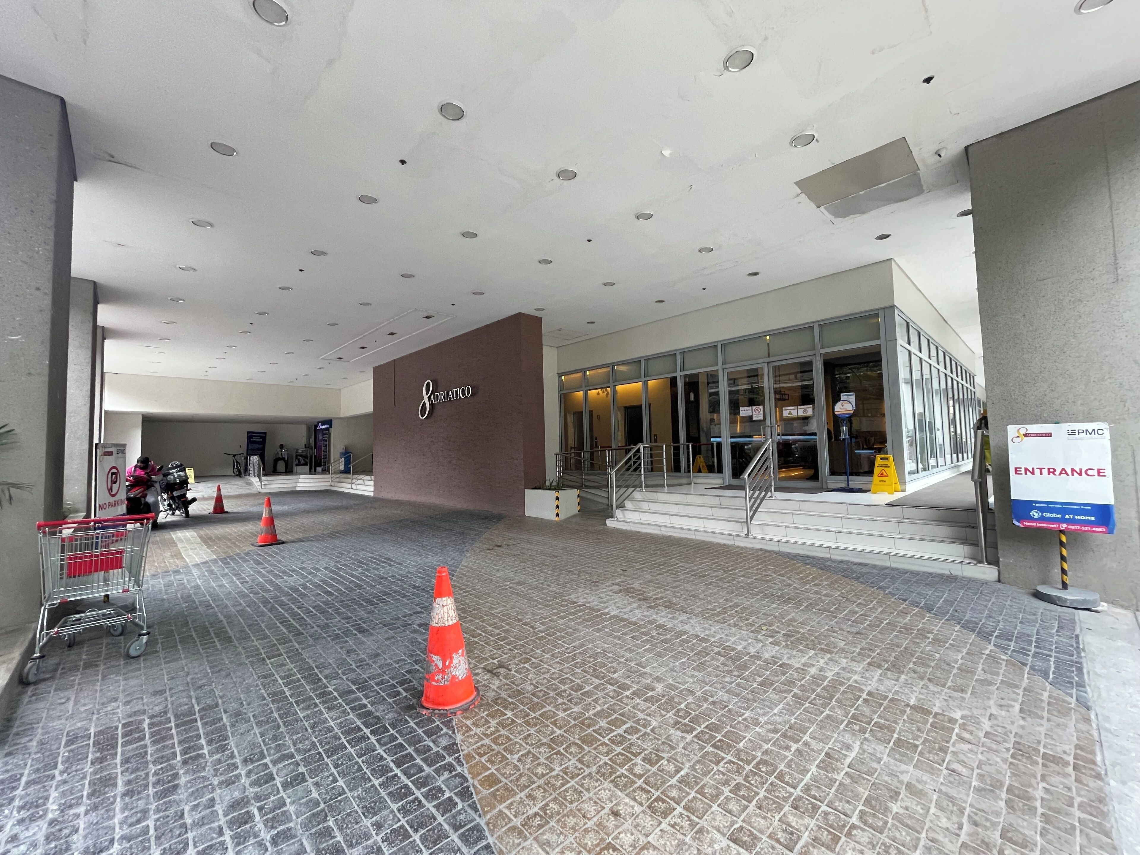A hotel entrance with a 'No Parking' sign, a shopping cart, and a 'No Smoking' sign.