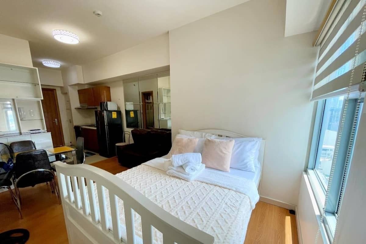 A hotel room with a bed, a desk, a chair, and a window.