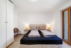 Une chambre à coucher avec un lit, deux tables de chevet avec des lampes, une chaise et une armoire.