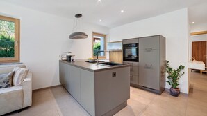 Una cocina moderna con una isla central, horno empotrado y zona de comedor con mesa y sillas.