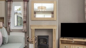 A living room with a fireplace, a television, and a sofa. - Maple Lodge (Newton Abbot)